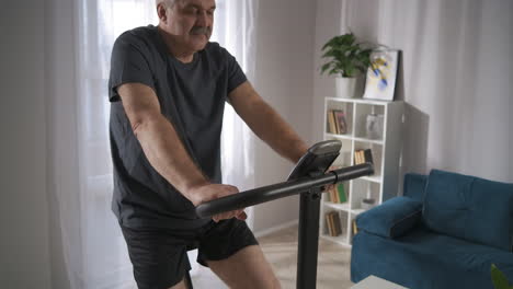 healthy-middle-aged-man-is-training-with-spinning-bike-at-home-at-weekend-spinning-pedals-in-living-room-cardio-workout